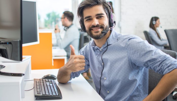 Happy male customer service operator showing thumb up in office. Happy male customer service operator showing thumb up in office.